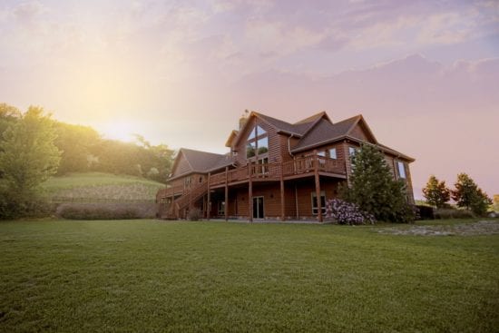 a large log home with a large lawn in front of it .