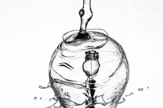 a black and white photo of water pouring into a glass .