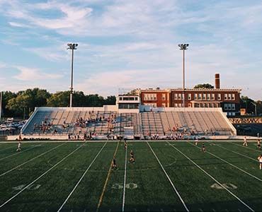 an aerial view of a football field with a stadium in the background .
