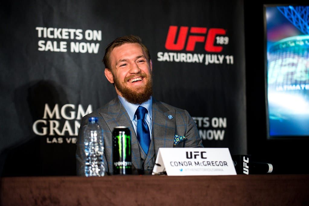 a man in a suit and tie is sitting at a table with a can of monster energy drink .