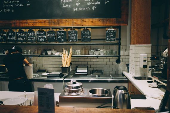 a kitchen in a restaurant with a chalkboard above the counter .