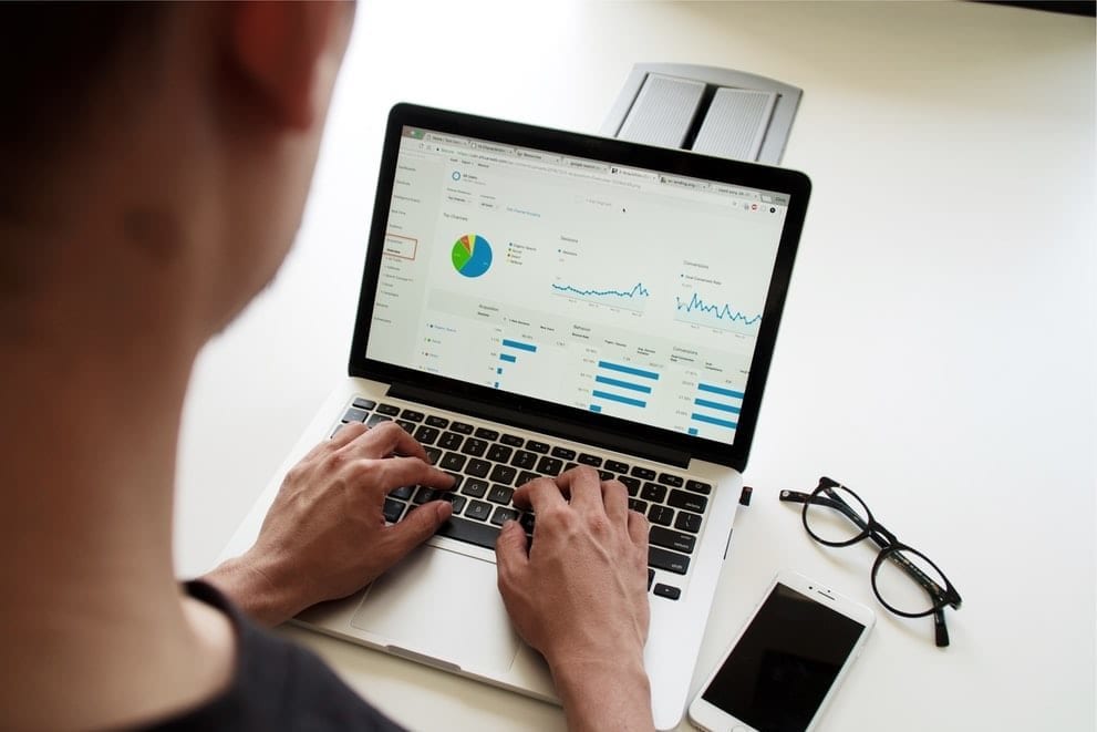 a man is typing on a laptop computer with a graph on the screen .