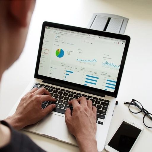 a man is typing on a laptop computer with a graph on the screen .