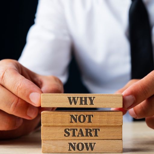 a man is holding wooden blocks with the words `` why not start now '' written on them .