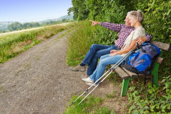 a man and a woman are sitting on a bench looking at the landscape .