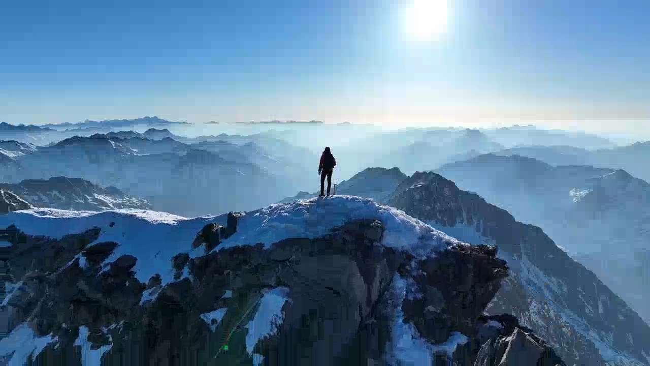 a person is standing on top of a snow covered mountain .