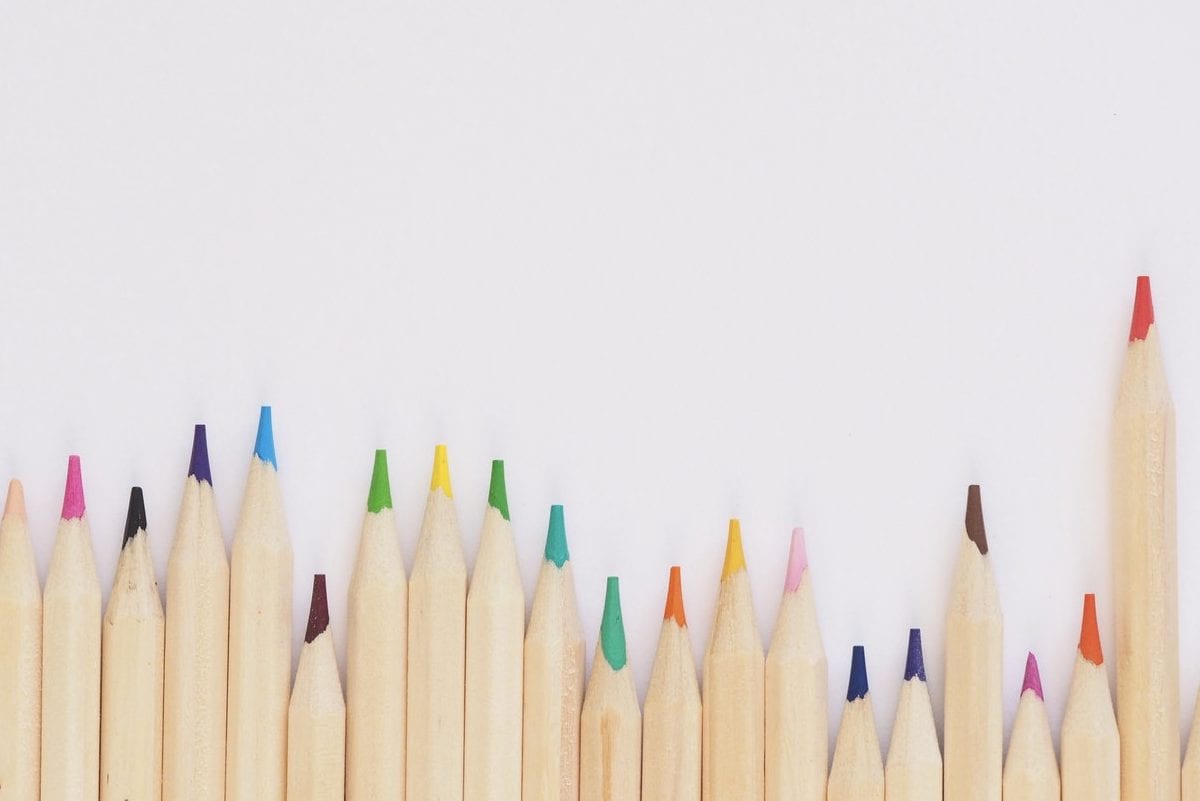 a row of colored pencils are lined up in a row on a white background .