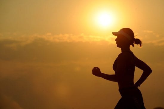 a silhouette of a woman running at sunset .