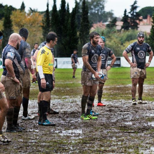 a group of rugby players are standing on a muddy field .