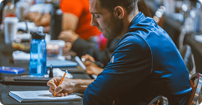 a man in a blue shirt is writing in a notebook