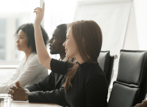 a woman is raising her hand to answer a question