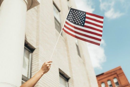 a person is holding an american flag in front of a building .