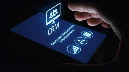 a hand is holding a smart phone with a screen that says customer relationship management .