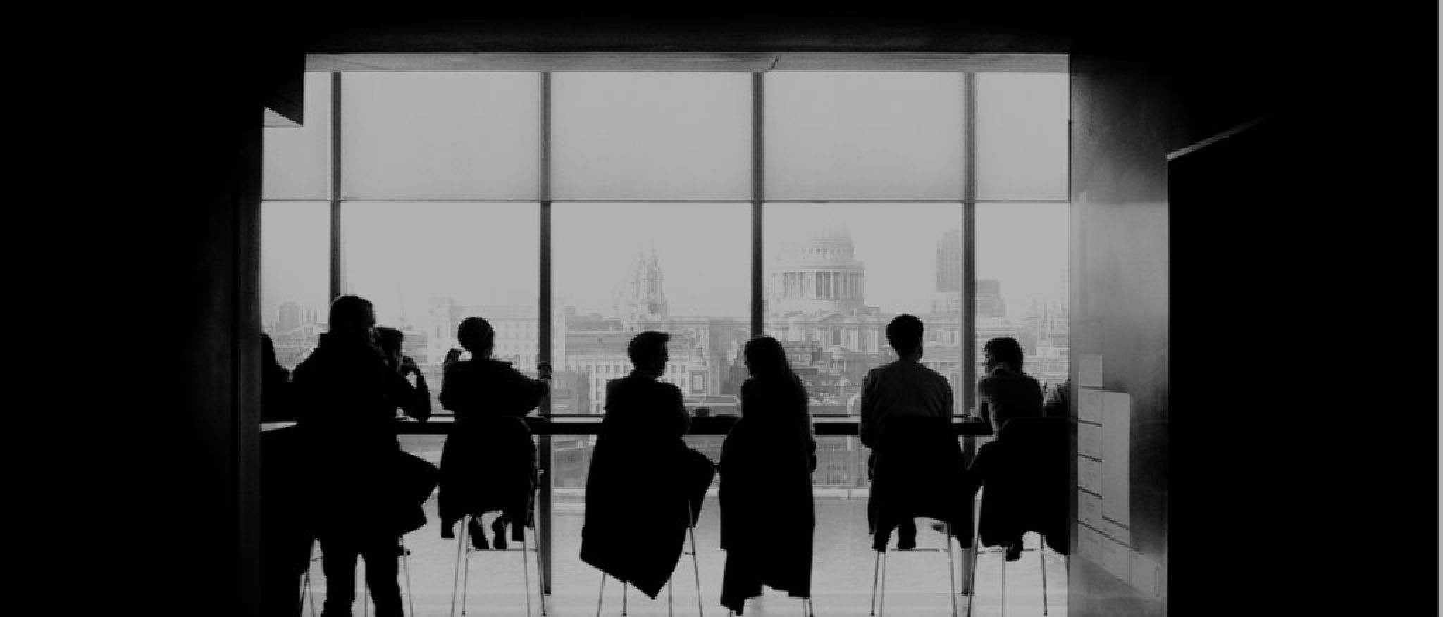 a group of people are sitting at a table in front of a large window .