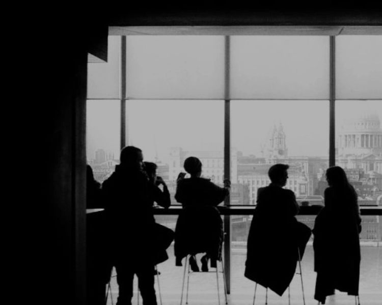 a group of people are sitting at a table in front of a large window .