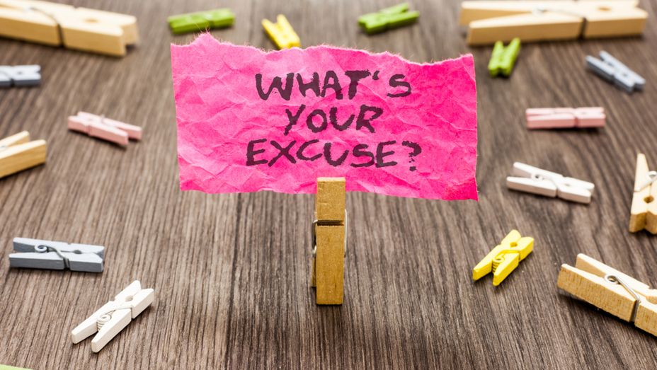 a pink piece of paper with the words `` what 's your excuse '' written on it is sitting on a wooden table .