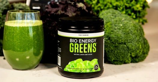 a jar of bio energy greens next to a glass of green juice .