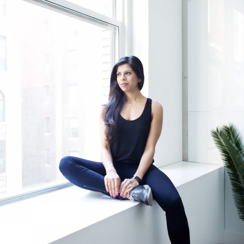 Build a bigger business image of woman in a white room staring out a window overlooking city buildings