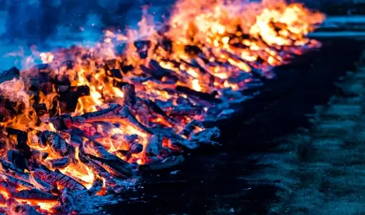 A long row of burning wood and embers, glowing orange and red.