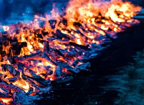 A long row of burning wood and embers, glowing orange and red.