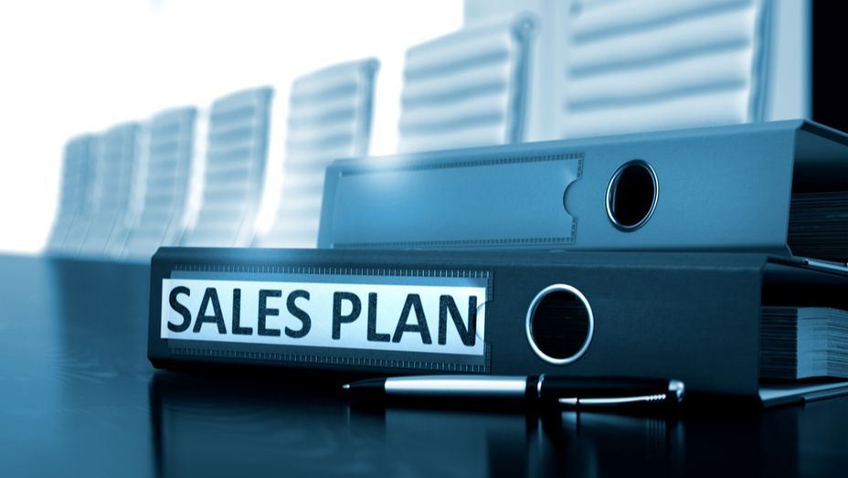 a sales plan binder with a pen on a table .