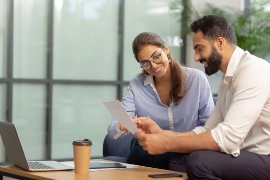a man and a woman are sitting at a table looking at a piece of paper .