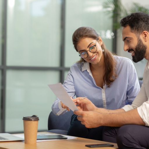 a man and a woman are sitting at a table looking at a piece of paper .