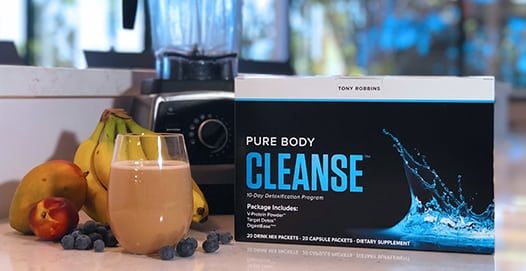 a box of pure body cleanse is sitting on a counter next to a glass of milk and fruit .