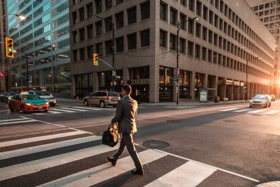 a man in a suit is walking across a city street .