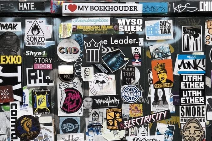 a wall covered in lots of stickers and graffiti .