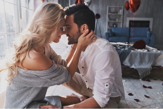 a man and a woman are kissing in a living room .