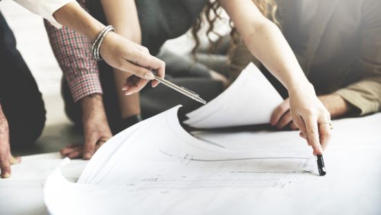 a group of people are sitting on the floor looking at a blueprint .