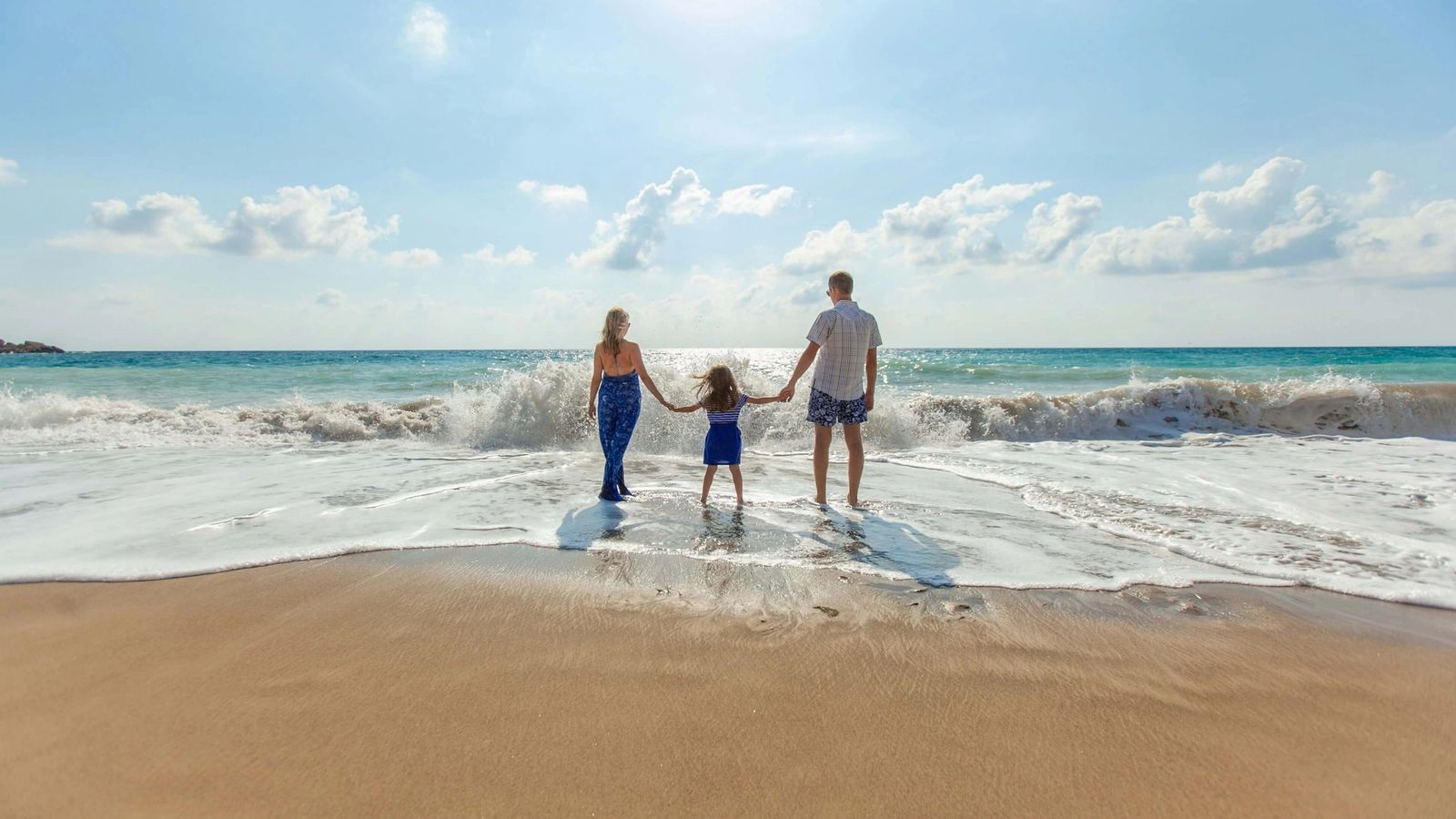 a family is walking on the beach holding hands .