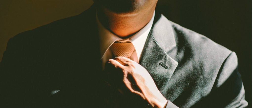 a man in a suit and tie is adjusting his tie .