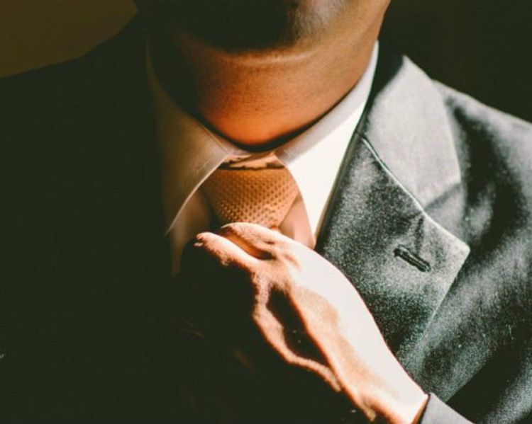a man in a suit and tie is adjusting his tie .