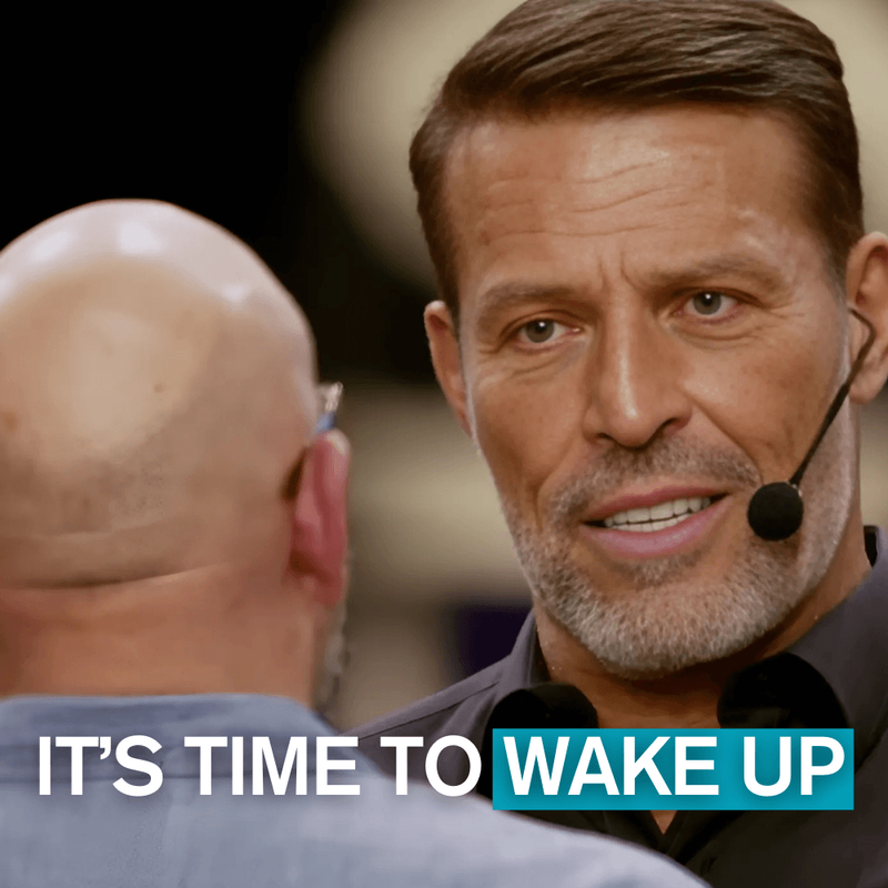 A man identified as Tony Robbins wearing a headset microphone and smiling, faces a bald man whose back is to the camera. Text: "IT'S TIME TO WAKE UP".