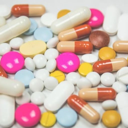 a pile of colorful pills and capsules on a white surface .