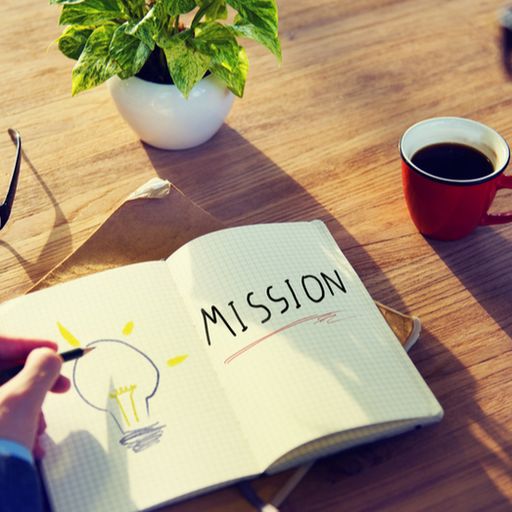 a man is writing in a notebook with the word mission written on it .