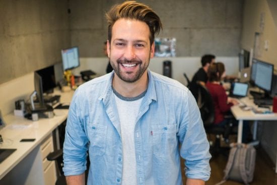 a man in a denim shirt is smiling in an office .