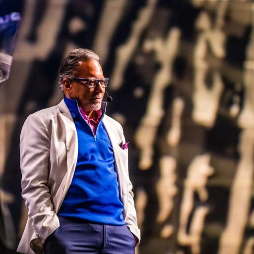 a man in a blue sweater and white jacket is standing in front of a podium .