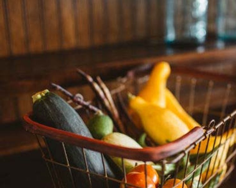 a basket filled with vegetables is sitting on a wooden table .