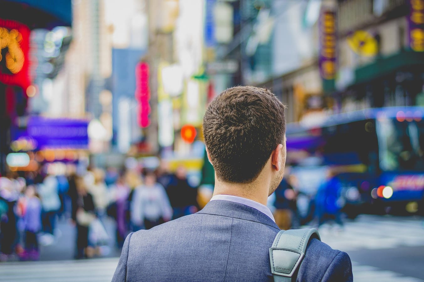 a man in a suit is walking down a city street .