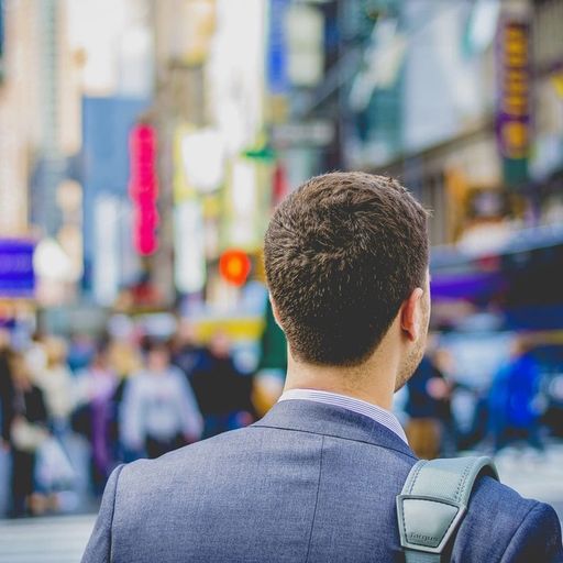 a man in a suit is walking down a city street .
