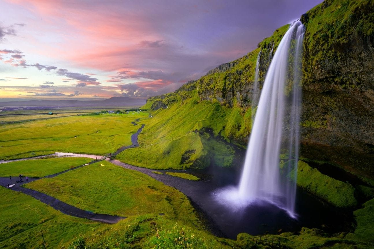 there is a waterfall in the middle of a green field .