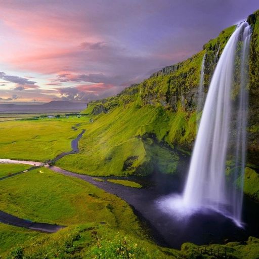 there is a waterfall in the middle of a green field .