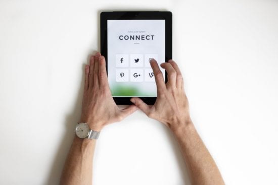 a person is holding a tablet with social media icons on it .