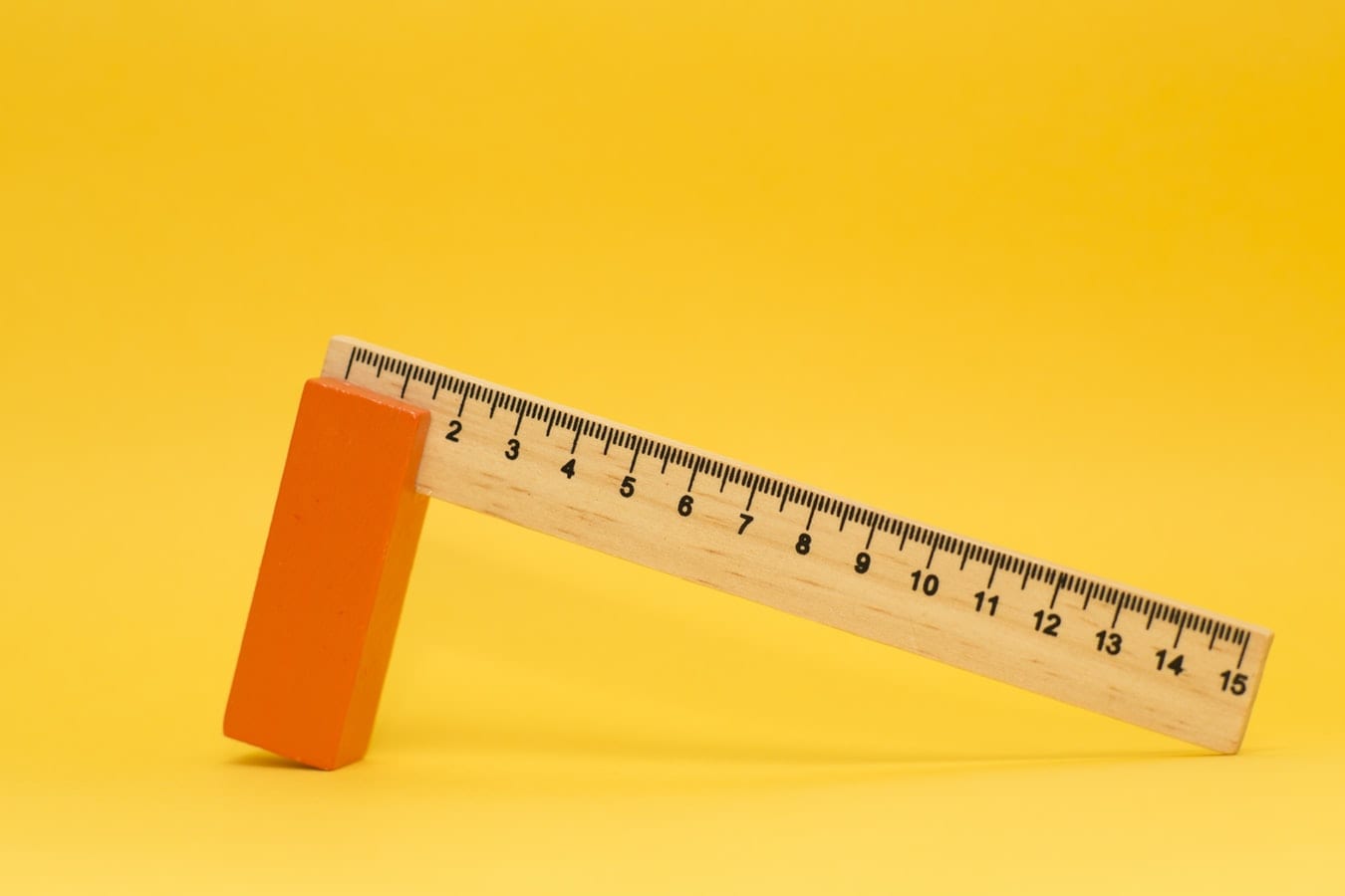 a wooden ruler with an orange block on a yellow background .