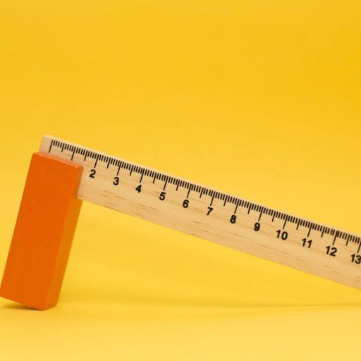 a wooden ruler with an orange block on a yellow background .