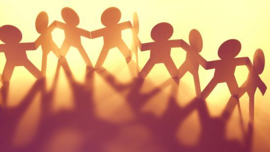 a group of paper people are holding hands in a row .