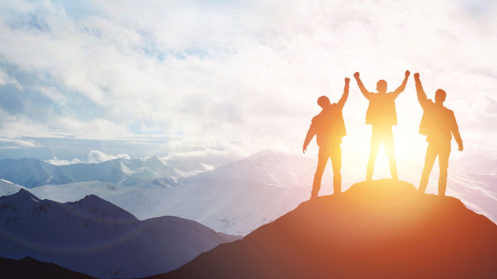 a group of people are standing on top of a mountain with their arms in the air .